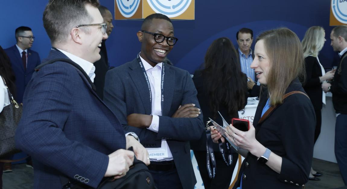 Three individuals talking and laughing at a medical conference